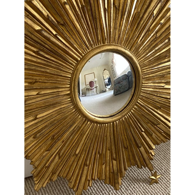 An Italian artisan crafted gilt wall mirror with a striking carved sunburst design embellished with a series of radiating...