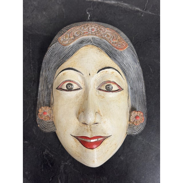 Design Plus Gallery presents an Indonesian Hand-Carved Wood Mask. Sculpted from wood, the mask portrays a serene female...