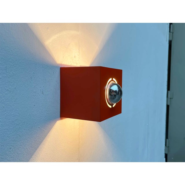 Space Age wall lamp in a special color. The lamp impresses with its simple cubic shape. The metal frame as a reflector of...