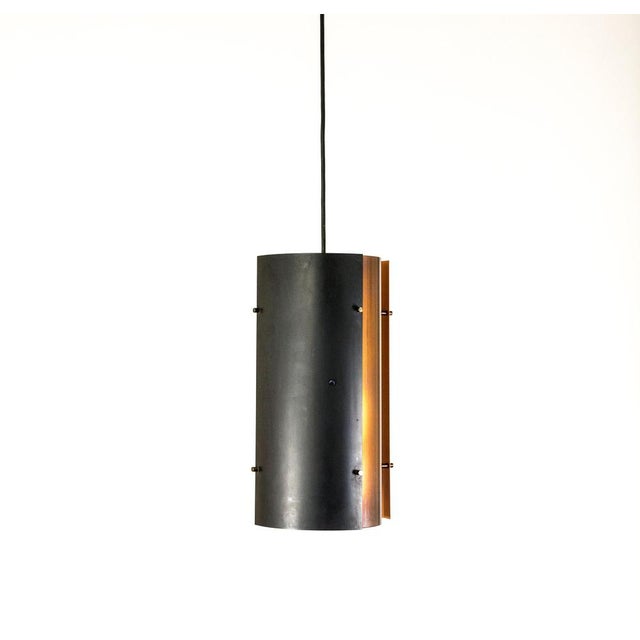 Copper and black colored pendant by Fog & Mørup. The lamp consists of four segments: two black ones with orange on the...