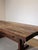 Impressive rustic dining table crafted from solid wood, featuring a substantial plank top and a traditional trestle-style...