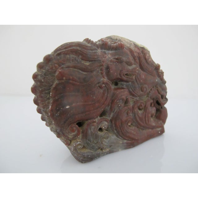 Old Chinese red Shoushan stone carving depicting a double dragon beast in sculpted waves. Heavily textured showing raw,...