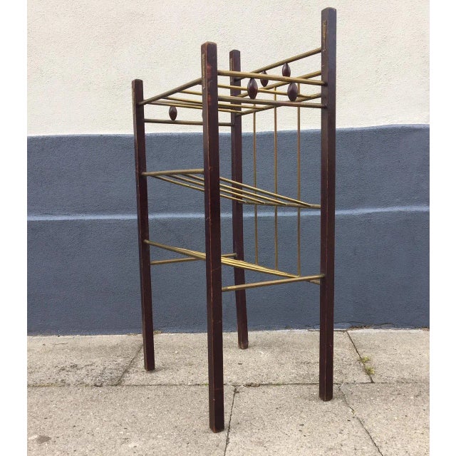 This Art Deco magazine rack or shelf was made in Vienna in the 1920s by a craftsman. It is made from stained wood and brass.