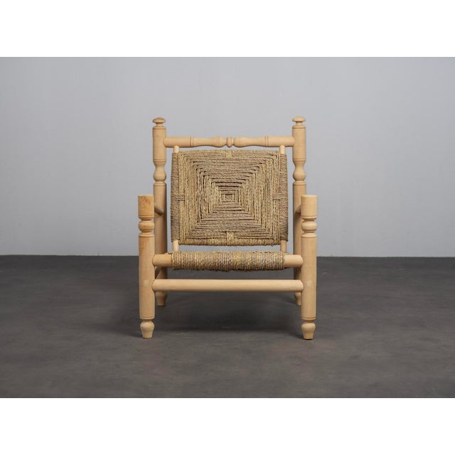 A distinctive french lounge chair from the 1970s, combining a beautifully turned wooden frame with an intricately woven...
