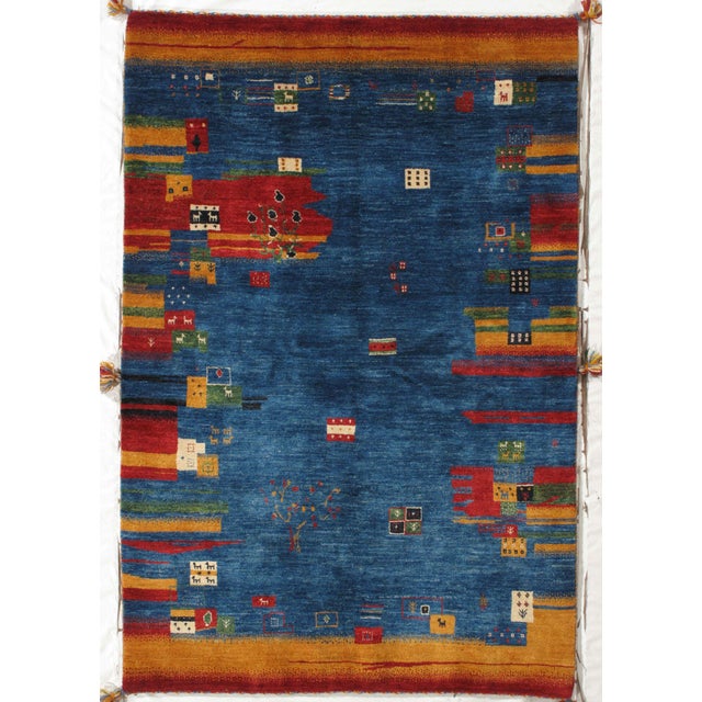 Vintage Persian hand-knotted Lori Gabbeh wool rug featuring a deep blue field accented with vibrant tribal motifs and...