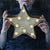 The Star in my hands by Marianna Foster | Oil on Board Portrait of a person holding a star-shaped light. For Sale
