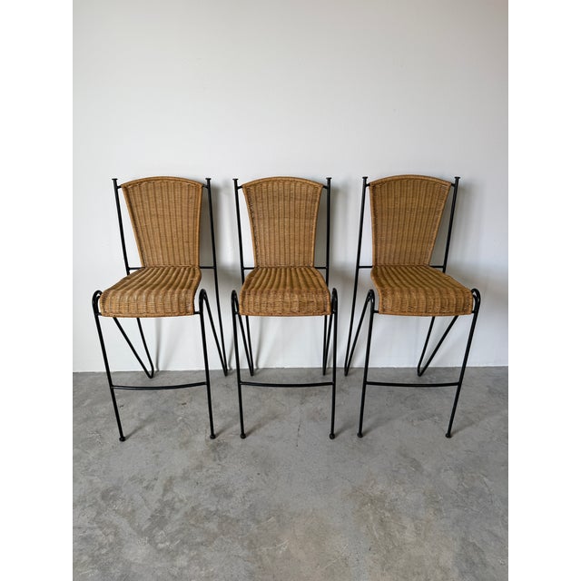 This 1970's Frederic Weinberg Style Rattan & Iron Bar Stools - Set of 3 features beautifully woven natural rattan seats...