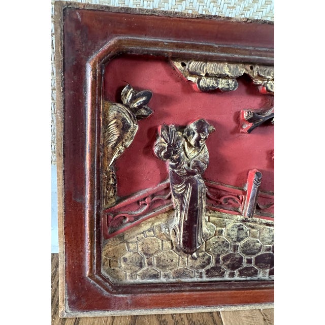 Chinese carved architectural wood panel featuring a figural courtyard scene with traditional dress, foliage, and stylized...