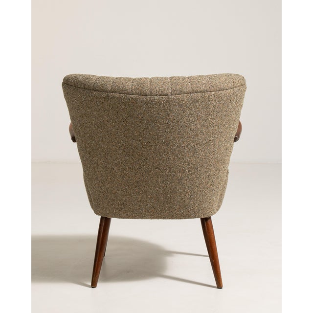 A refined Danish armchair featuring a shellback form, reflecting early Scandinavian modern design. The curved back...