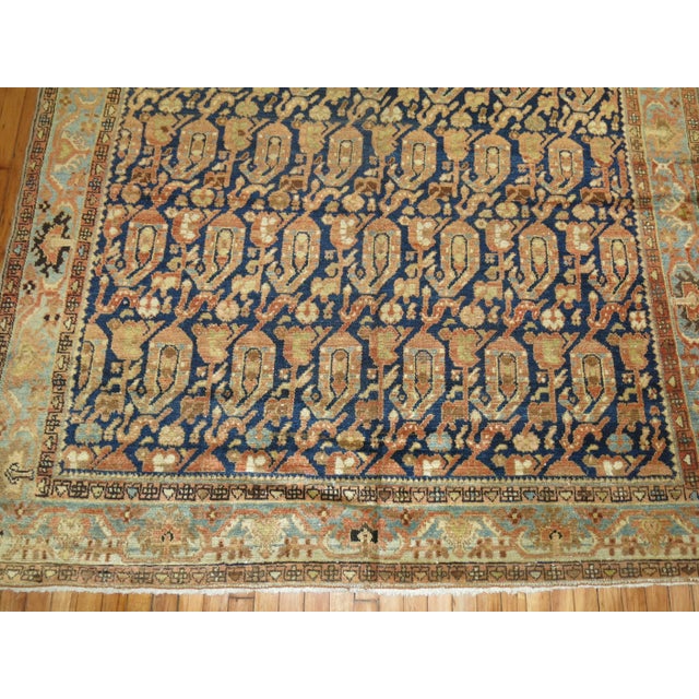 A Persian Malayer gallery rug featured a large-scale all-over paisley design in blues and terracotta, circa 1920....