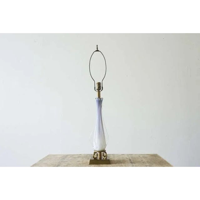 This table lamp, of brass and Murano glass, features a delicate floral motif. The white and violet glass expertly swells...