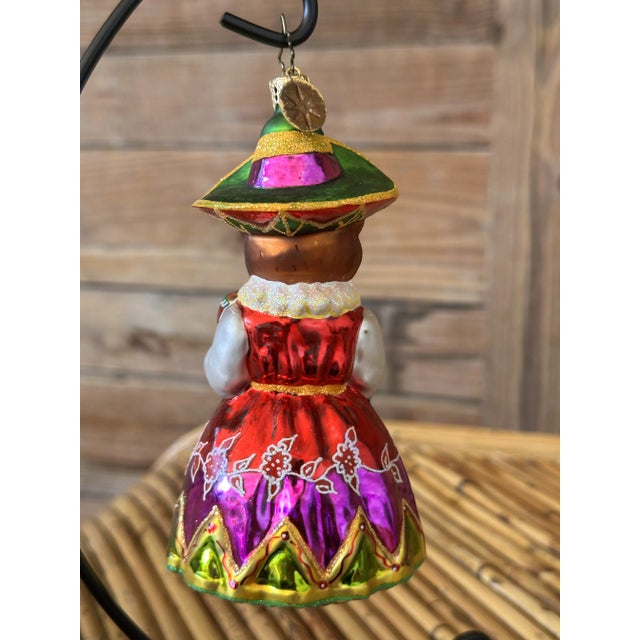 Delight in the festive charm of this hand-painted Christopher Radko Seniorita Fiesta glass ornament, meticulously crafted...