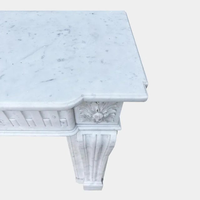 A petit antique 19th century Carrara Marble fireplace in the Louis XVI manner The console jambs twin fluted terminating in...