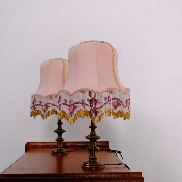 This pair of vintage table lamps features a brass base and pink lampshades decorated with beaded fringe. 1960s/1970s...