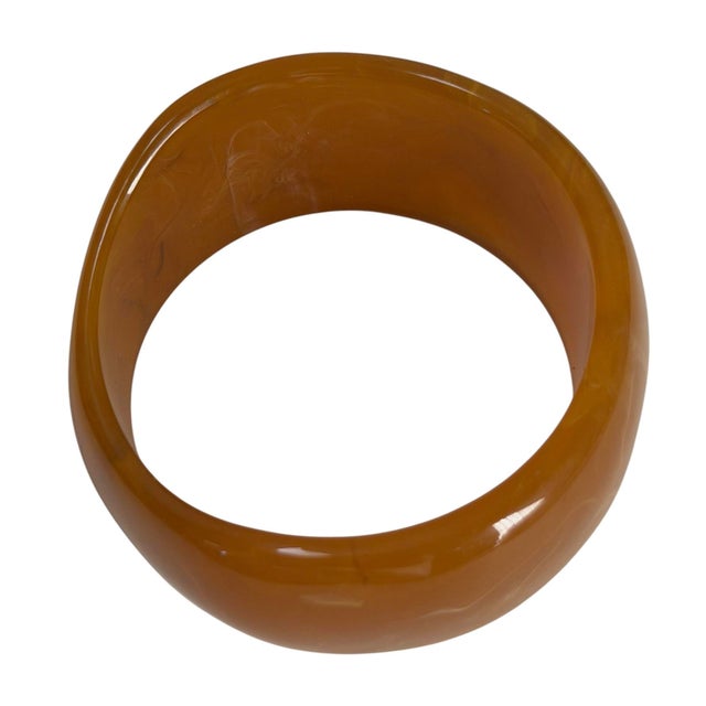 This vintage bakelite bangle bracelet features a rich caramel-orange color with a subtle marbled pattern. Why the shape...