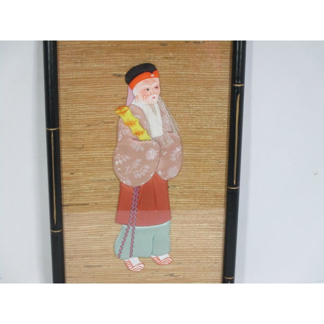 A three-dimensional textile art of an Oriental male figure. It is professionally framed behind glass, mounted on a tan...