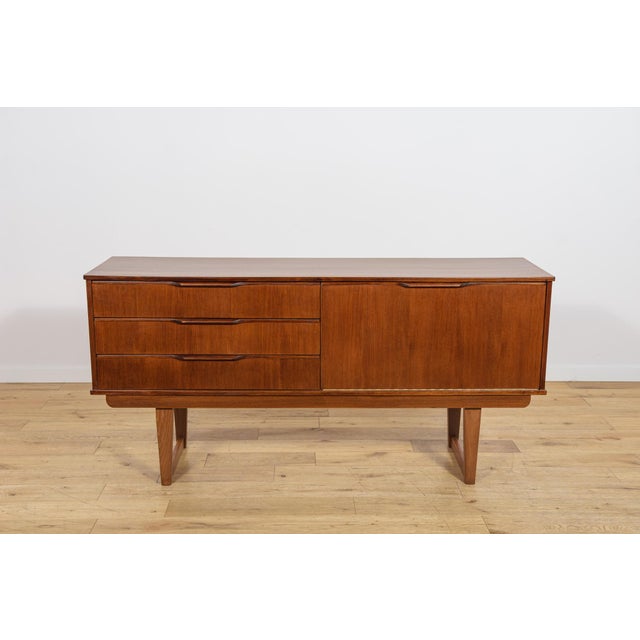 This compact sideboard was manufactured in the United Kingdom during the 1960s. The piece is distinguished by its elegant,...
