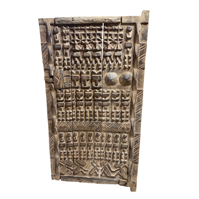 This vintage Dogon granary door from Mali features intricate carved relief figures—standing Nommo ancestors , breasts...
