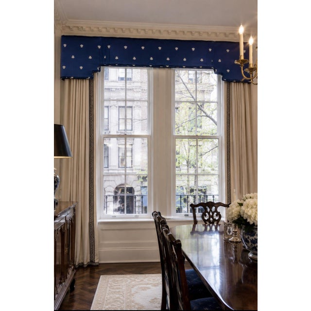 Striking custom upholstered window cornice in a rich navy blue fabric adorned with repeating white bee motifs. The...