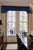 Striking custom upholstered window cornice in a rich navy blue fabric adorned with repeating white bee motifs. The...