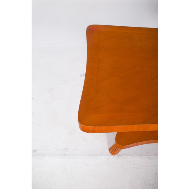 Dining table with centre leg. The top has a rectangular shape with curved edges and a light varnished finish. The base is...