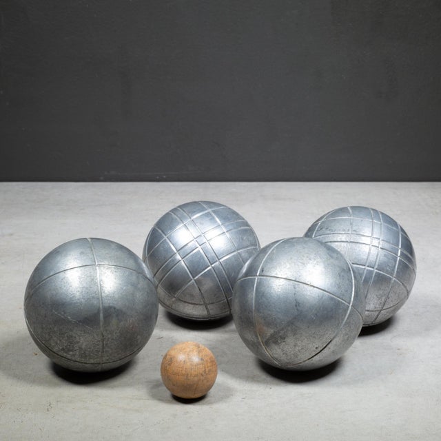 ABOUT A French mid-century set features four heavy metal pétanque boules and one wooden target ball crafted by the iconic...