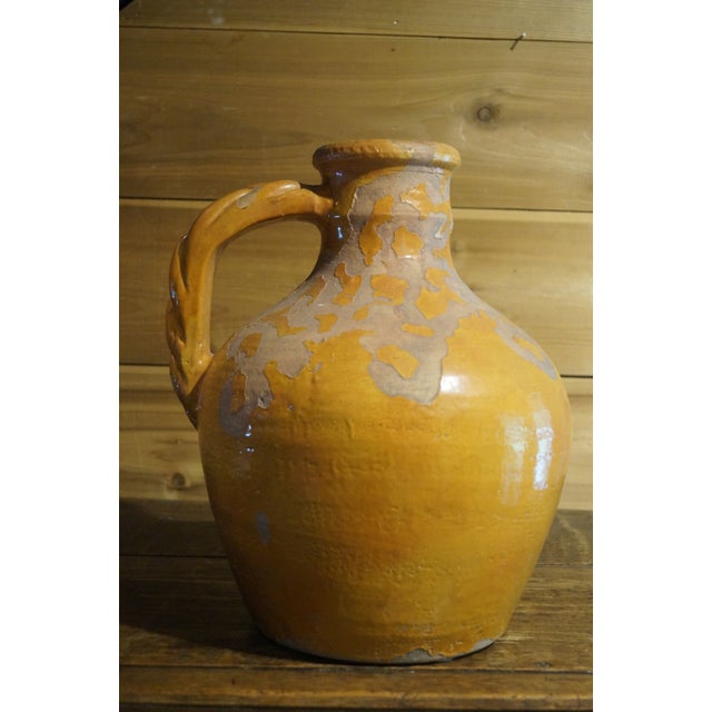 A beautiful yellow glazed pottery jug with a thick braided handle. In good vintage condition. Measures 13.5 inches tall x...