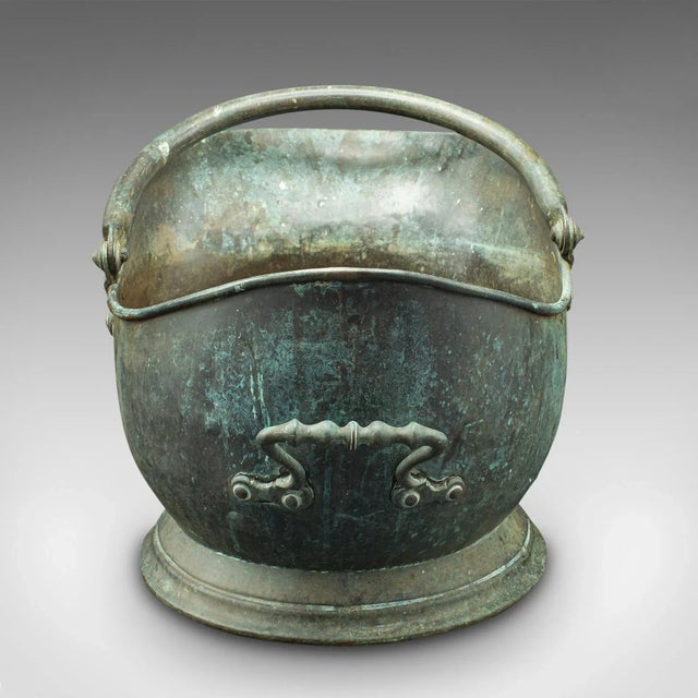 This is an antique country house coal scuttle. An English, patinated copper fireside store or fuel keeper, dating to the...