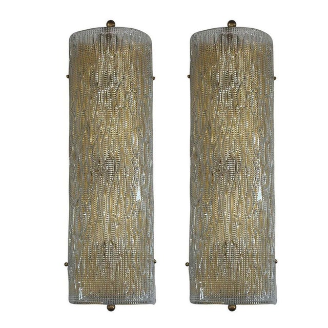 A set of three vintage Murano glass sconces mounted on a brass frame; the glass having a unique bent design with lined...