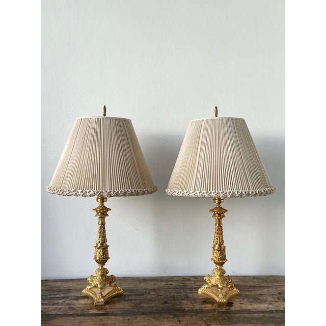This masterfully crafted pair of Empire-style candlestick lamps exudes neoclassical grandeur, featuring substantial gilt...