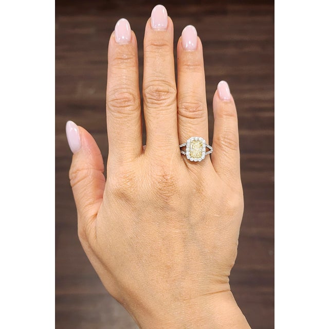 A stunning 2.01 carat radiant-cut yellow diamond is beautifully complemented by 0.72 carats of round-cut white diamonds,...