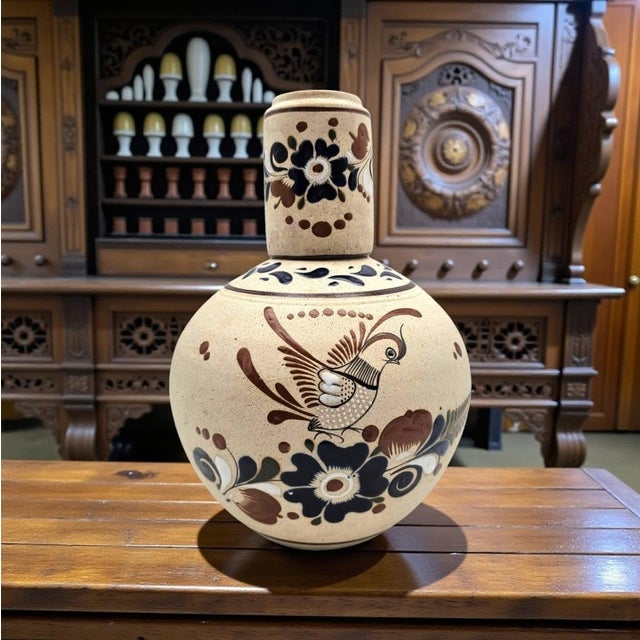 A traditional Tonalá, Jalisco water jug formed in warm buff earthenware and hand-painted with stylized bird and floral...