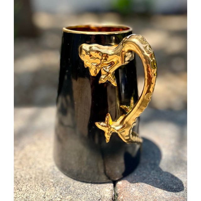 J & C Bavaria mug featuring a striking black glaze with gilded dragon-shaped handle, which extends along the side of the...