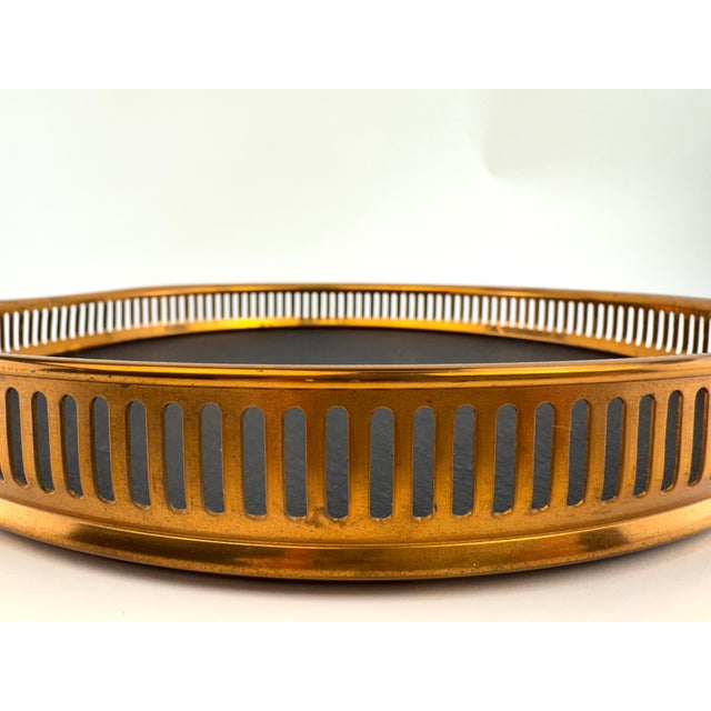 A refined mid-century serving tray featuring a pierced brass-tone gallery surrounding a textured black faux leather...