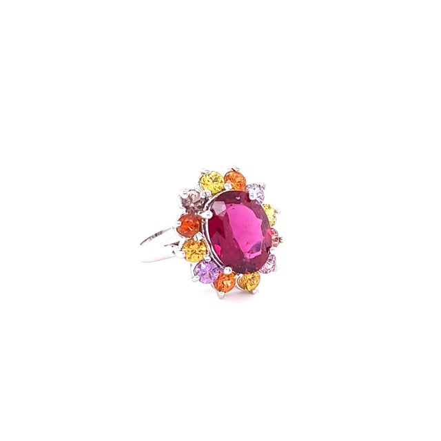 This ring has a 4.23 carat Oval Cut Hot Pink Tourmaline (Rubellite) and is elegantly surrounded by 12 Round Cut Multi-...
