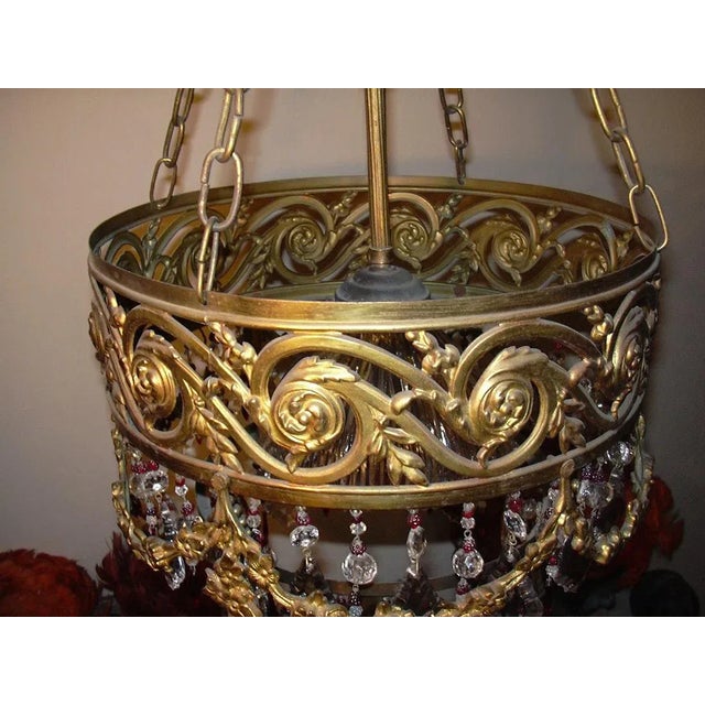 This antique gilded cascading crystal chandelier with red raspberry accents was produced in the 1920s. This unique vintage...