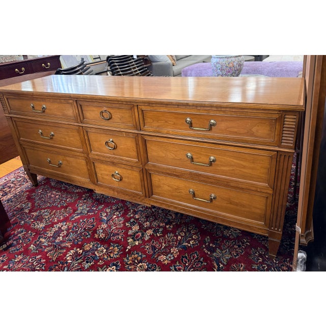 Classic vintage Kindel nine drawer dresser with a warm wood finish, framed drawer fronts, fluted details, and brass ring...