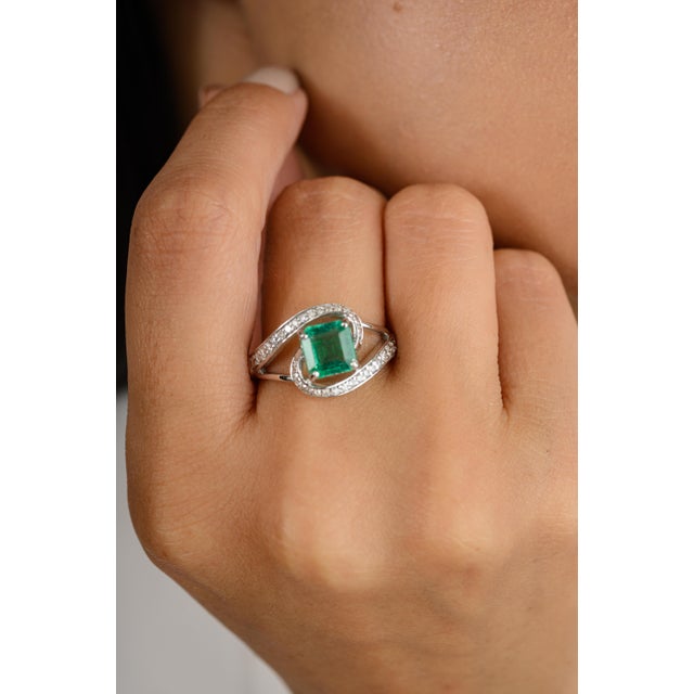 This stunning 18k white gold ring features a vibrant square-cut emerald as its centerpiece, beautifully accented by...