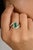 This stunning 18k white gold ring features a vibrant square-cut emerald as its centerpiece, beautifully accented by...