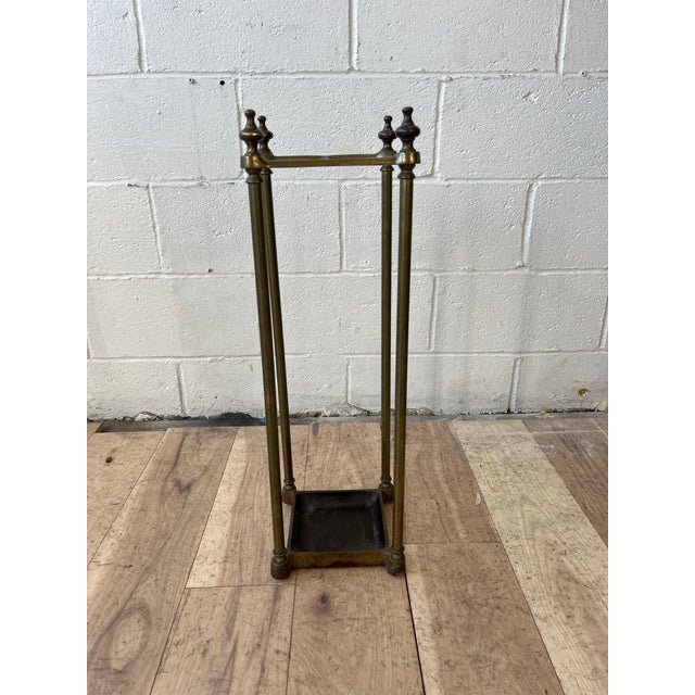 Elegant vintage brass umbrella and walking stick stand featuring a tall architectural frame with four slender columnar...
