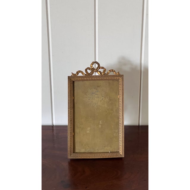 Large antique brass frame featuring an elegant bow detail and rich patina.