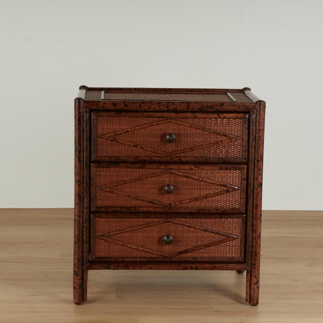 Handsome vintage British colonial stands crafted with faux burnt bamboo frames with three drawers, grasscloth panels all...