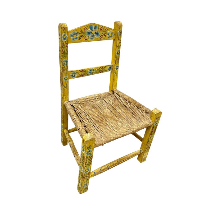 A delightful vintage Mexican folk art child’s chair, hand-painted in a cheerful palette of golden yellow, sky blue, and...