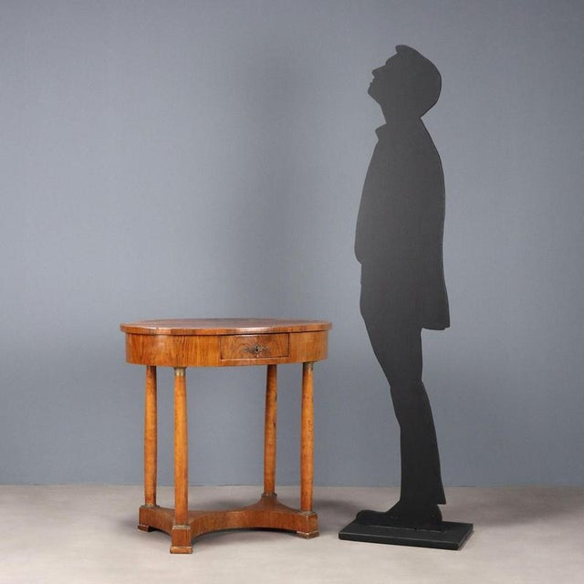 Empire walnut coffee table. Oval top with drawer in the lower band, four turned legs with chiseled and gilded bronze bases...