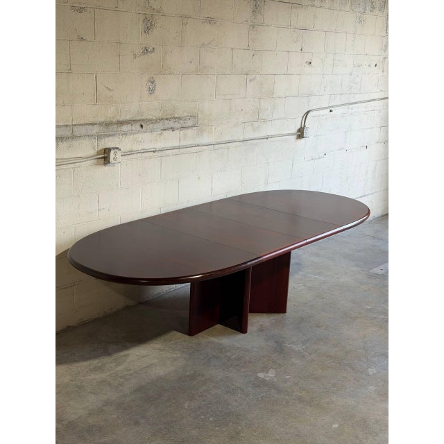 This dining table features a stunning oval top and a striking cross-pedestal base. The elegant design incorporates...