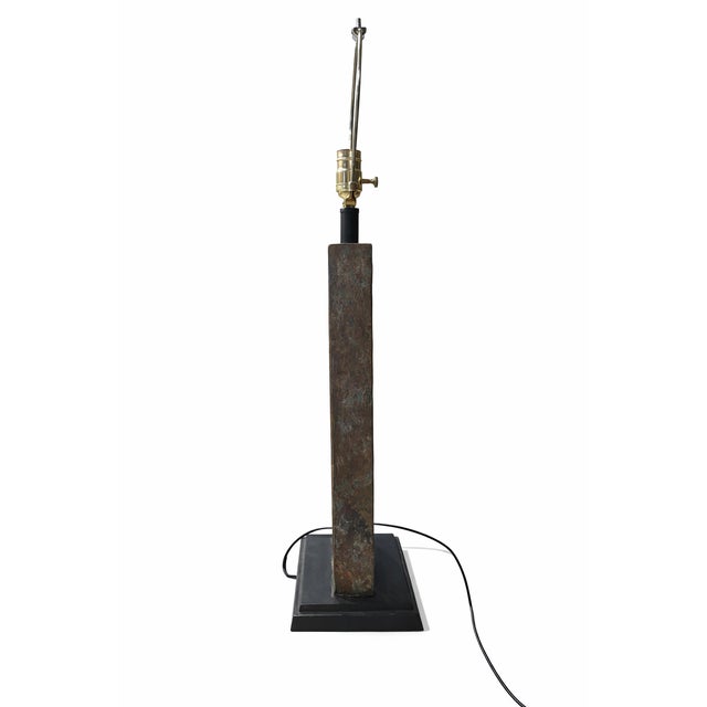 Striking sculptural table lamp featuring a rectangular open-frame body crafted from natural slate in earthy tones of moss...