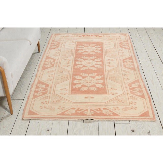 This is a vintage Turkish Oushak rug from the Mid 20th Century. The piece was hand-knotted.