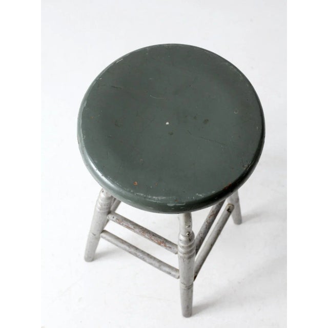 This is an antique painted swivel seat stool. The classic turned leg stools features silver metallic paint on its base...