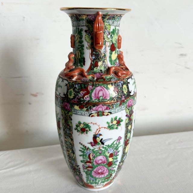 This intricately designed vase features vibrant floral patterns with colorful birds and butterflies. The decorative...