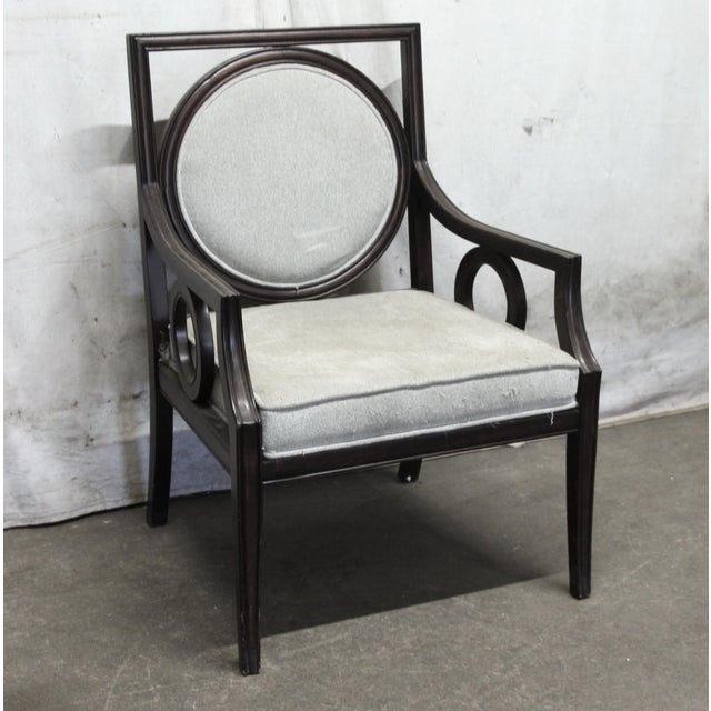 Dark wood tone framed chair with circular carvings on the side and gray upholstery. There is some wear and fraying in the...